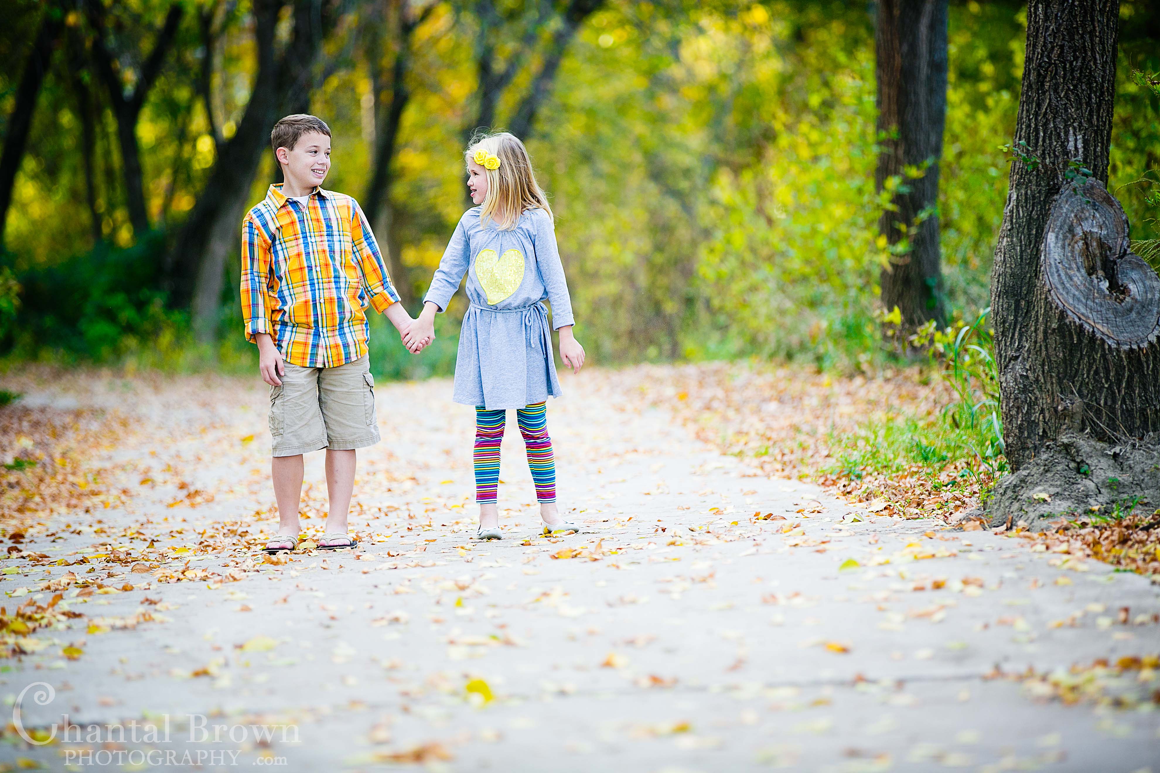 Brother and Sister holding hands on sidewak beautiful fall leaves colors children portrait photography at Breckinridge Park in Richardson Texas