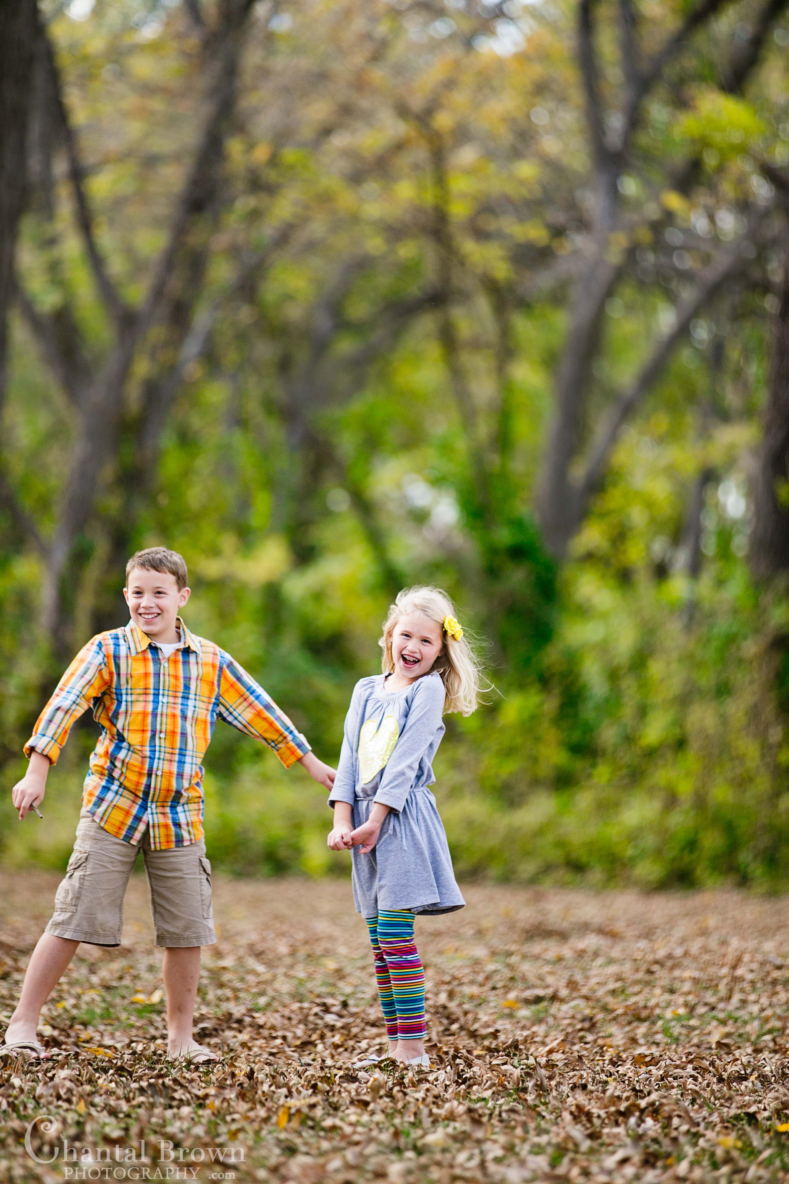 Children portrait photography at Breckinridge Park in Richardson Texas smiling and having a wonderful time playing in fall colors field covered with brown leaves
