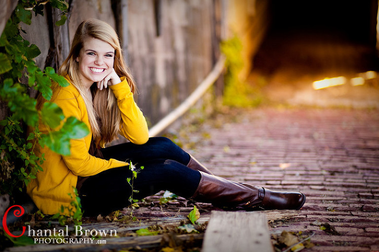 Dallas Plano Richardson Texas Senior Portrait taken in Stock Yard Ft Worth a girl wearing bright yellow shirt smiling