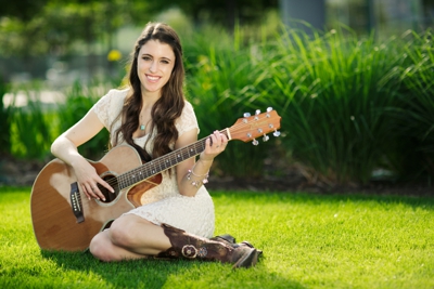 Prosper High School Senior portrait photographer a student holding a guitar in downtown Dallas by Windspear performing art center.