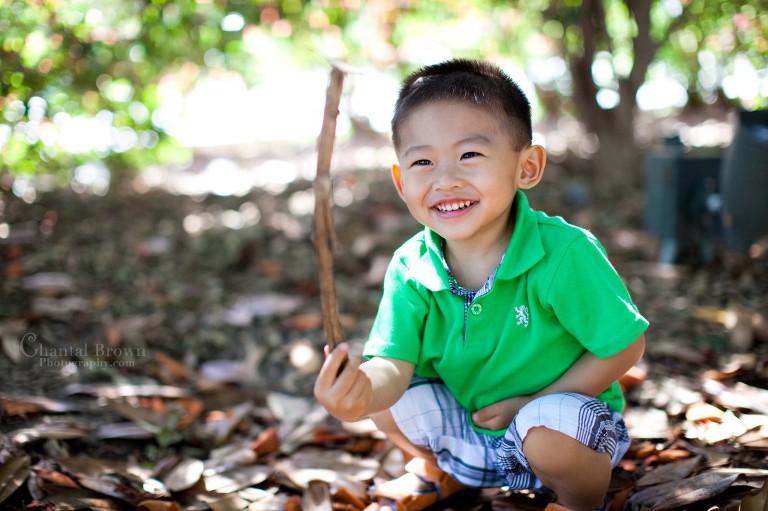 Little boy having too much fun laughing and playing with sticks at Dallas Aboretum Botanical garden
