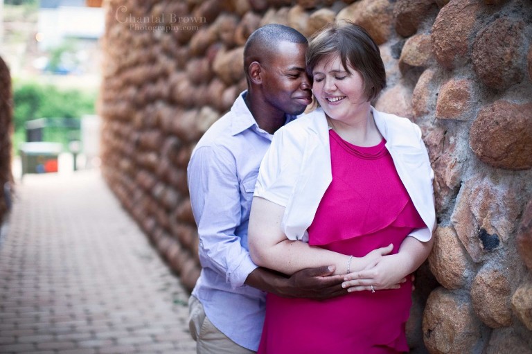 Engagement couple leaning on beautiful cobblestone gold and brown round brick wall in Medicine Park Lawton Oklahoma portrait photography