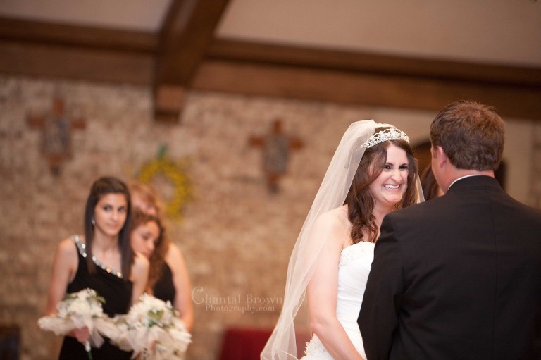 bride smiling at groom wedding ceremony at Holy Family Catholic Church in Lawton Oklahoma indoor