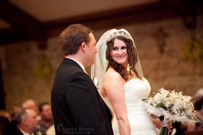 bride smiling at groom wedding ceremony inside Holy Family Catholic Church Lawton OK