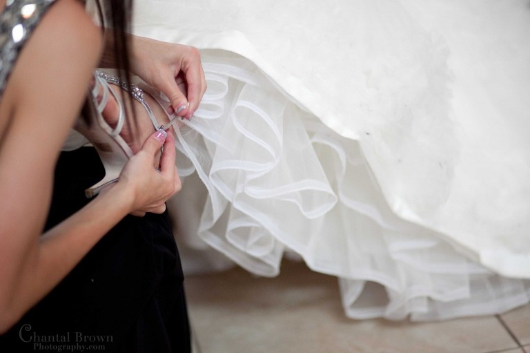 bridesmaid putting shoes on bride at Holy Family Cahtolic Church Lawton Oklahoma