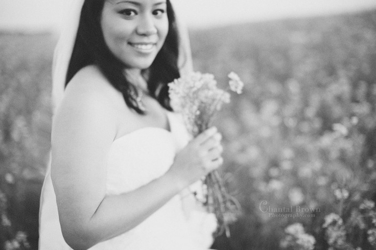 black and white bridal portrait at yellow flowers field in lawton oklahoma smiling and holding bouquet