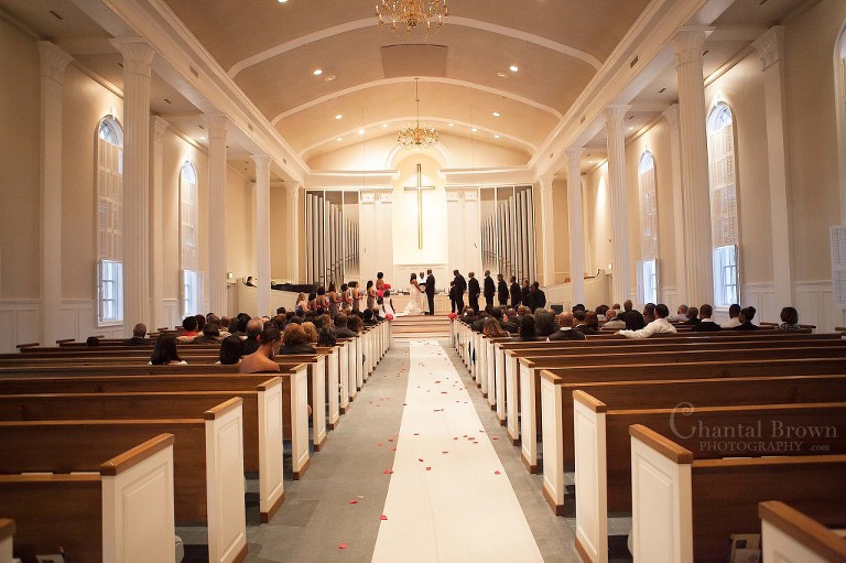 bride and groom getting married inside of beautiful Royal Lane Church wedding ceremony with large white pillars in Dallas Wedding Photographer