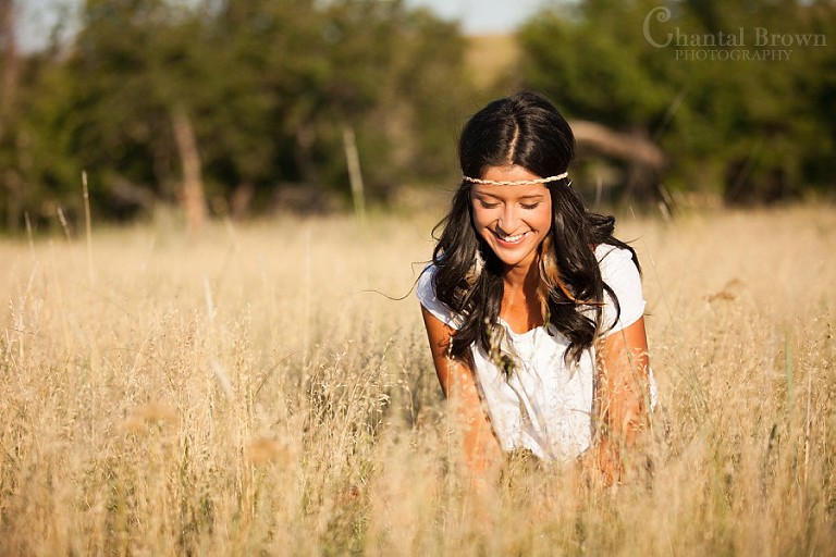 Hippie styled Plano senior portraits laughing in sunlight tall grass field
