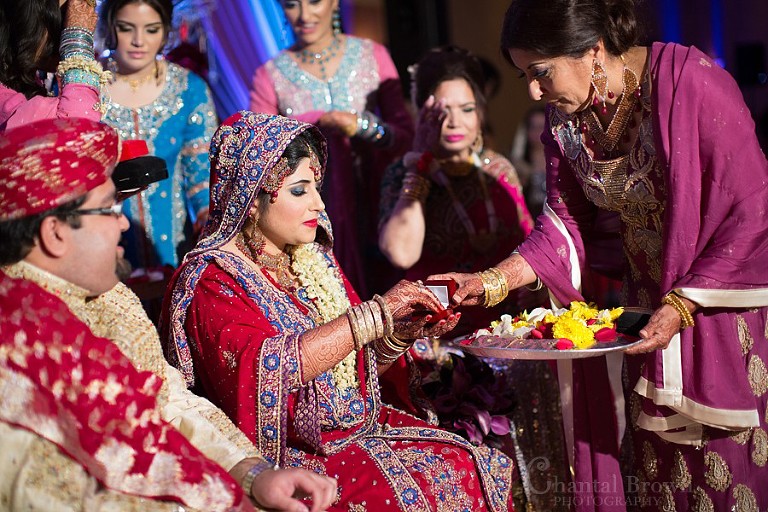 Stunning Indian wedding bride and groom exchanging wedding rings wearing traditional red sari fabrics with gold embroidery at Marriott Renaissance hotel in Richardson Texas