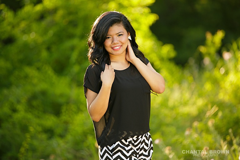 Carrollton senior portrait photographer of a beautiful high school girl taken out in the beautiful green field with pretty back light.
