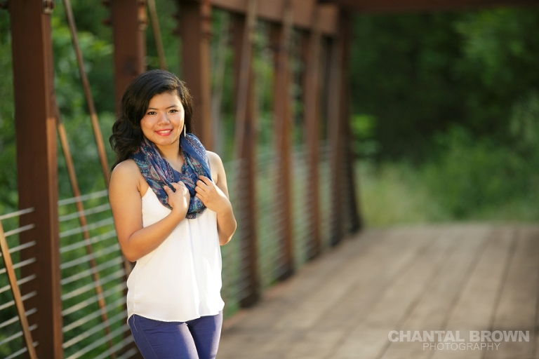 Dallas senior photographer a portrait of Lien standing on a brown bridge wearing a blue scarf during the golden sunset light at Richardson Texas Breckinridge Park by Chantal Brown Photography.