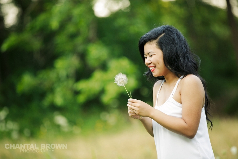 Plano senior photographer portrait of a girl holding a big dandelions smiling at the park by Chantal Brown Photography. 
