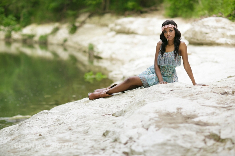 Allen senior photographer with a stunning Wylie high school senior picture of a student wearing baby blue dress and flower head band setting on a white rock by the water creek taken by the water creek by Chantal Brown Photography