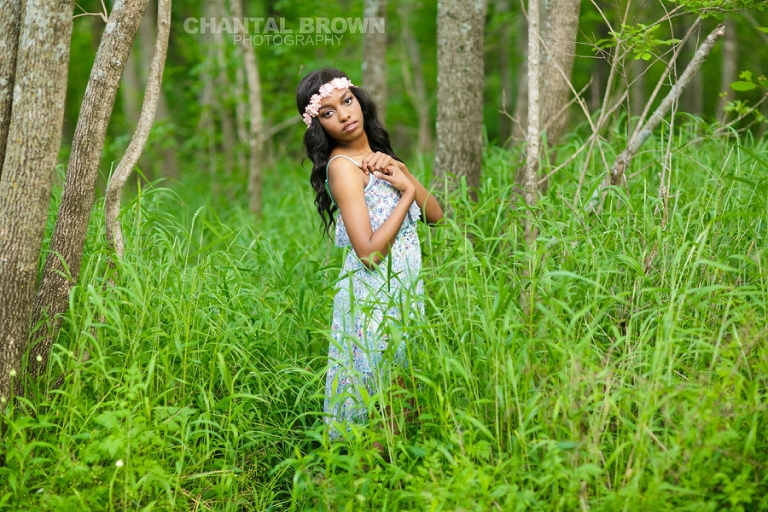 Dallas senior picture of Wylie East high school senior standing in beautiful tall green grass wearing a pink flower head piece and baby blue dress pretending she's in Twilight movie taken by Chantal Brown Photography