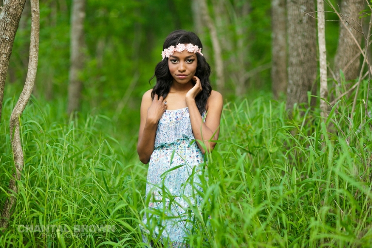 Dallas senior portrait of Wylie East high school senior standing in beautiful tall green grass wearing a pink flower head piece and baby blue dress pretending she's in Twilight movie taken by Chantal Brown Photography