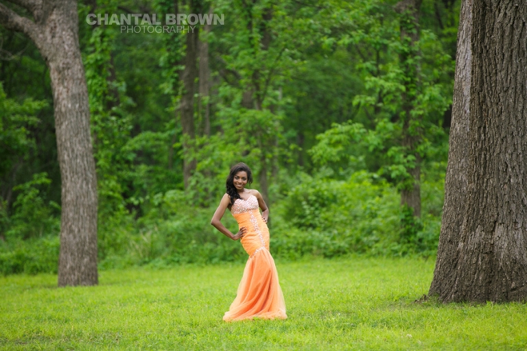 The best orange prom dress in Plano of a senior portrait standing out in the field  taken by Chantal Brown Photography.