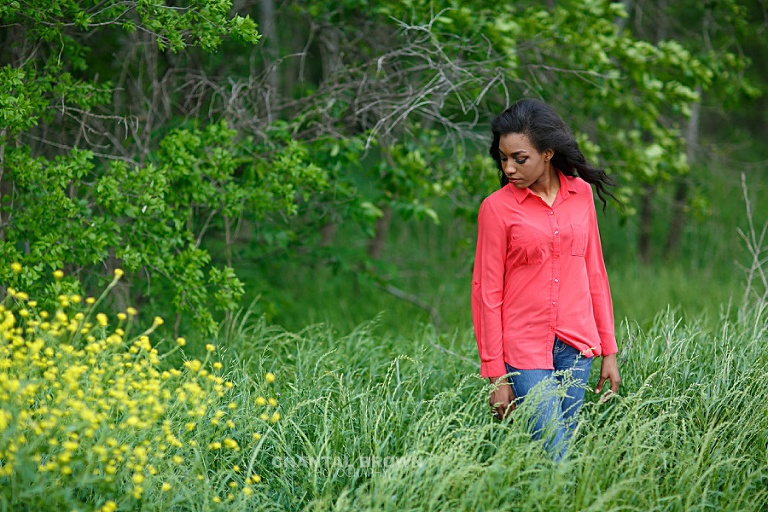 Wylie East high school student senior standing in long tall and green grass field with yellow flowers taken by Allen senior portrait photographer Chantal Brown Photography of Texas.