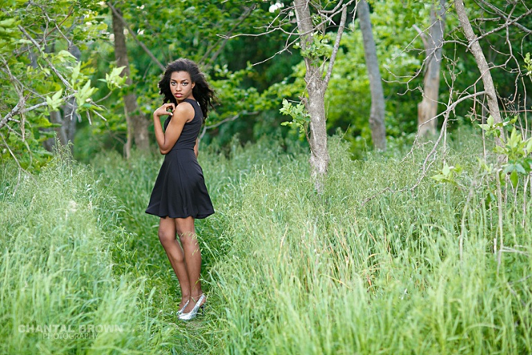 Pretty senior picture of a girl wearing little black dress standing in tall grass field taken by Frisco senior portrait photography of Chantal Brown Photography.
