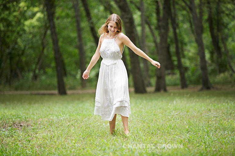 Plano high school senior photographer spinning a white dress in the field by Chantal Brown Photography.
