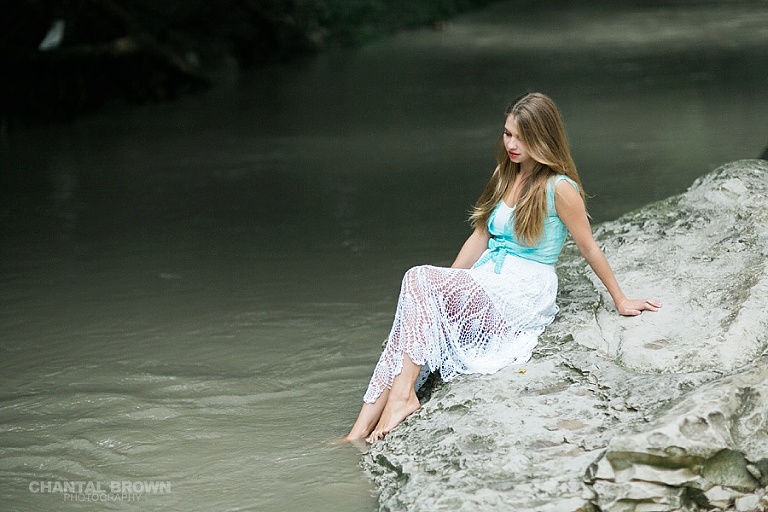 Addison senior portrait photographers high school sitting on white rock by the river taken by Chantal Brown of Addison Texas senior photographer.