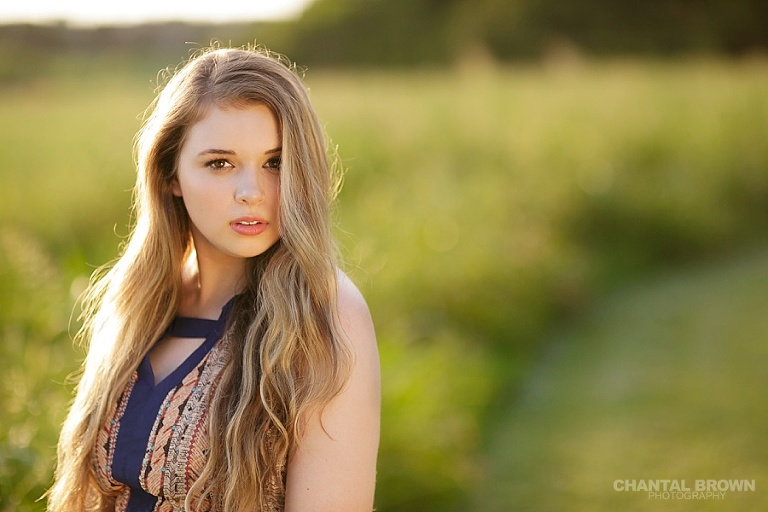 Golden sunset Dallas senior portraits with beautiful light of high school student standing in a big field taken by Dallas senior portraits photographer Chantal Brown.