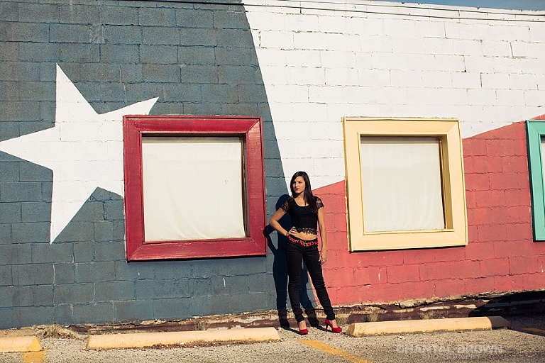 Senior portraits in Deep Ellum standing next to American flag wall in Dallas Texas.