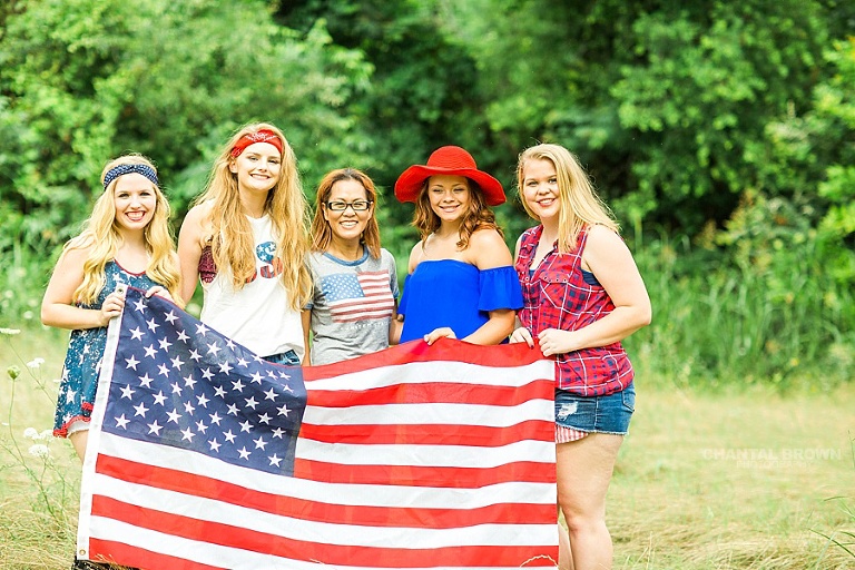The gorgeous 4th of July styled senior portraits group session taken by the best Chantal Brown photography in Dallas holding a big American flag with her senior models.
