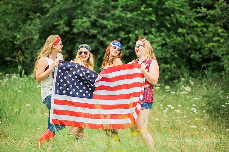 4th of July styled senior portraits holding an American flag in a tall grass field taken by Chantal Brown Photography.