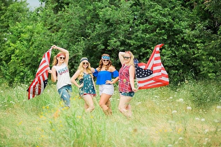 4th of July styled senior portraits for red white and blue American flag standing in tall grass field taken by Chantal Brown Photography.