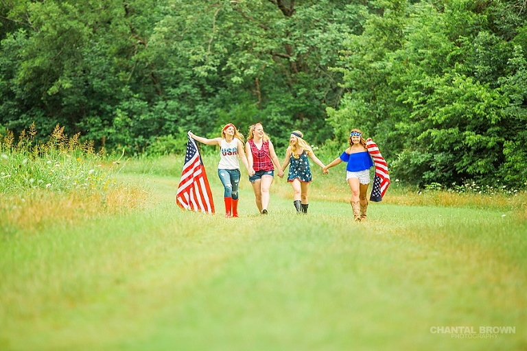 The best American flag styled senior portraits in Dallas walking in grass field.