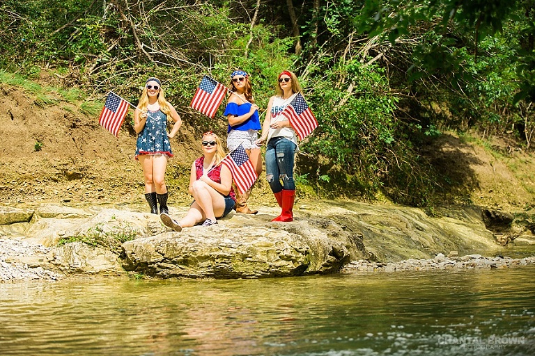 Happy 4th of July Dallas senior portraits taken by the water creek river the girls are holding American flags.