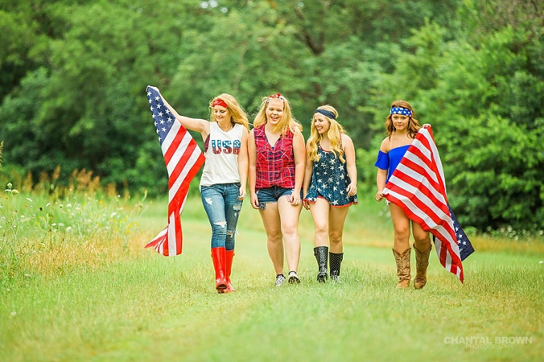 Independence Day styled senior portraits group photo shoot in Dallas walking in grass field holding American flags.