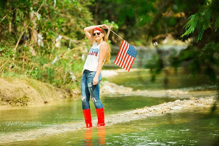 4th of July senior portraits holding American Flag taken in Dallas water creek river for a Plano high school student. She's also wearing all American outfit.