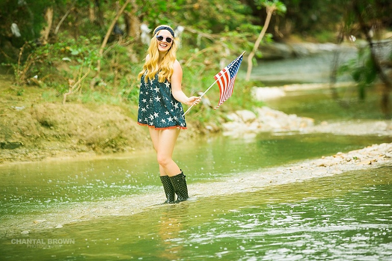 All American high school student senior portraits holding a small American flag taken in Dallas water creek river by Chantal Brown photography.