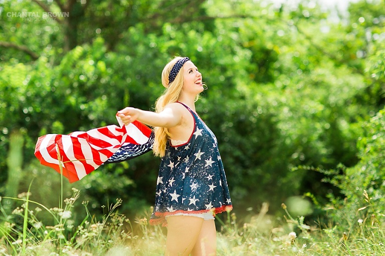 Flying American flag inspiration senior portraits photo shoot taken in Dallas tall grass field. Taken outdoor during high noon by Chantal Brown Photography.