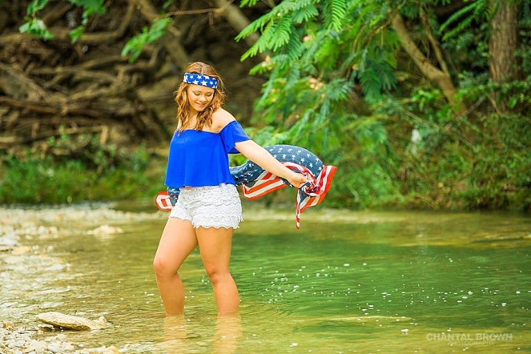 Holding American flag scarf inspiration senior portraits session taken in Dallas water creek river wearing very cute outfit.