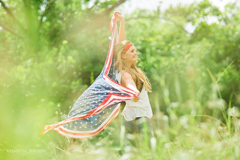 Happy Independence Day senior portraits holding an American flag scarf in Dallas grass field.
