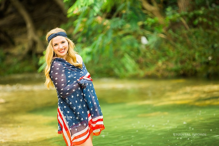 Independence Day senior portraits for an Allen high school senior student wrapped around an American flag scarf styled session. Taken in the water river creek by Dallas Chantal Brown Photography.