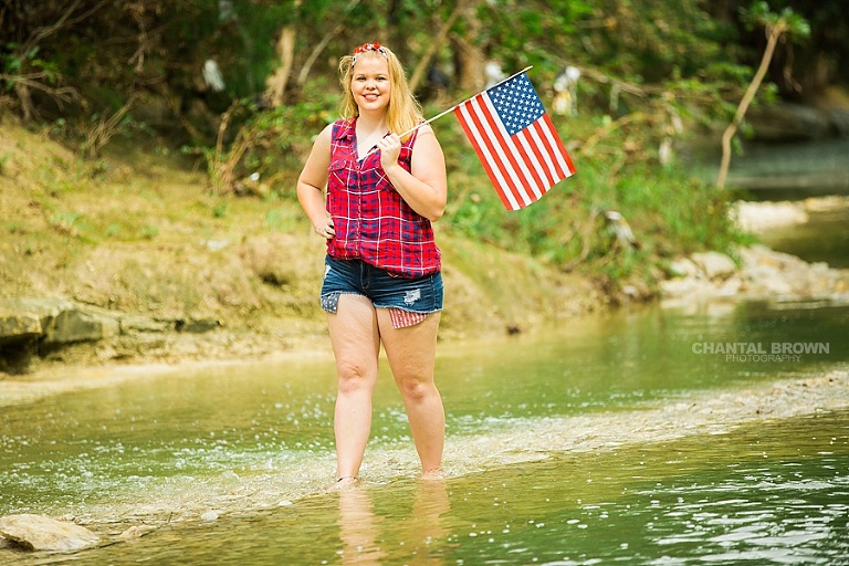 Very adorable red white and blue clothes. Wearing very patriotic summer outfit styled Dallas senior portraits standing in the water and holding an American flag outfit. www.chantalbrownphotography.com